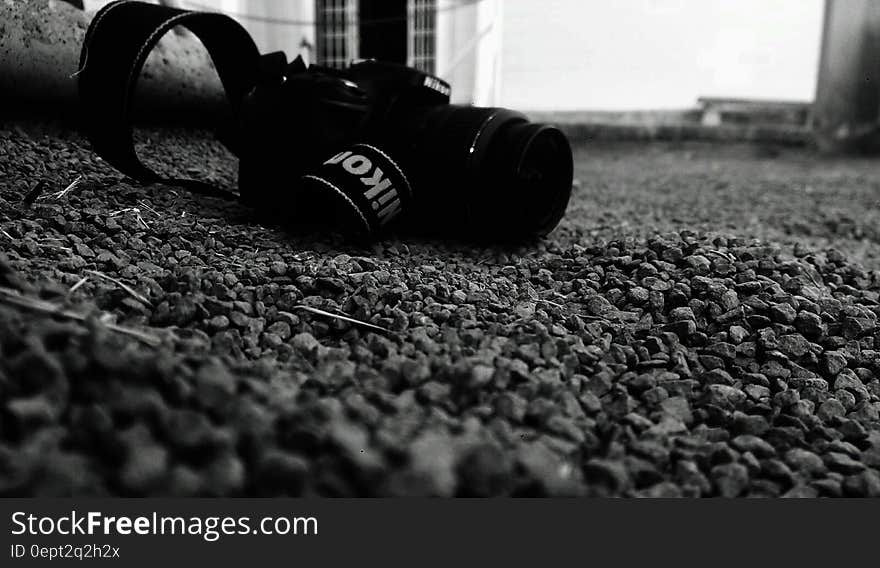 Nikon camera on pebbles on ground in black and white.