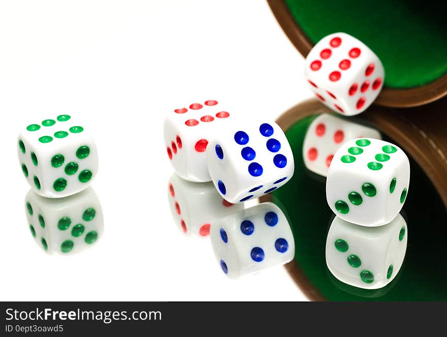 Close up of colorful dice and cup reflecting on mirror.