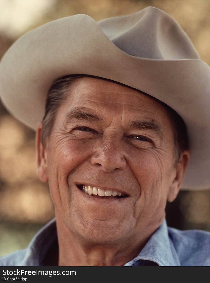 A portrait of president Ronald Reagan smiling with a hat on his head. A portrait of president Ronald Reagan smiling with a hat on his head.