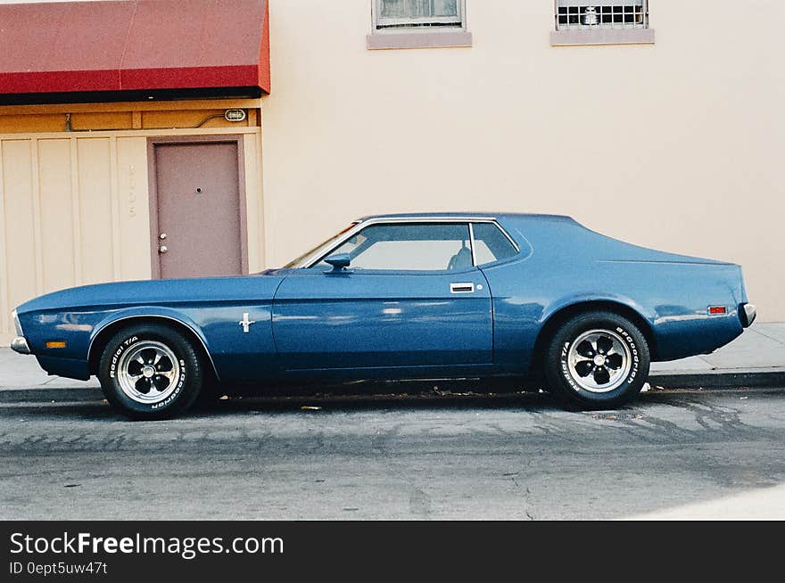 A blue mustang parked in front of a house.