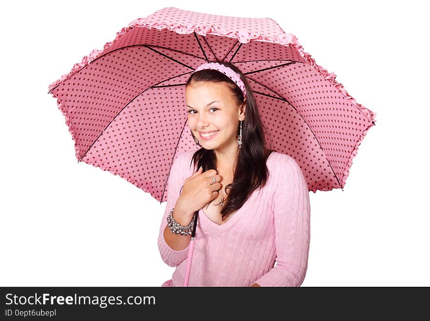 A smiling young woman under a pink polka dot umbrella. A smiling young woman under a pink polka dot umbrella.