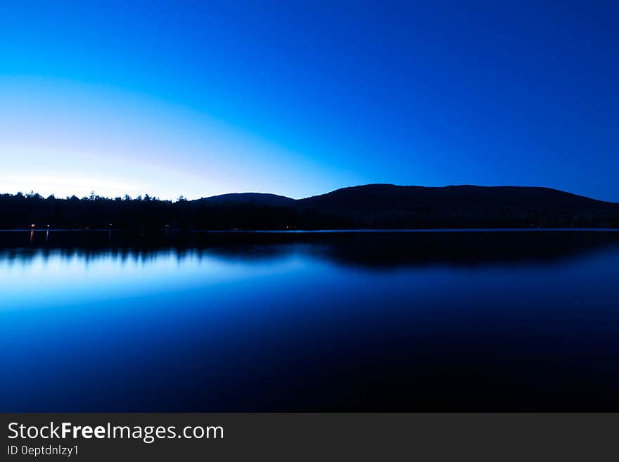 A blue lake with a dark blue sky at night.