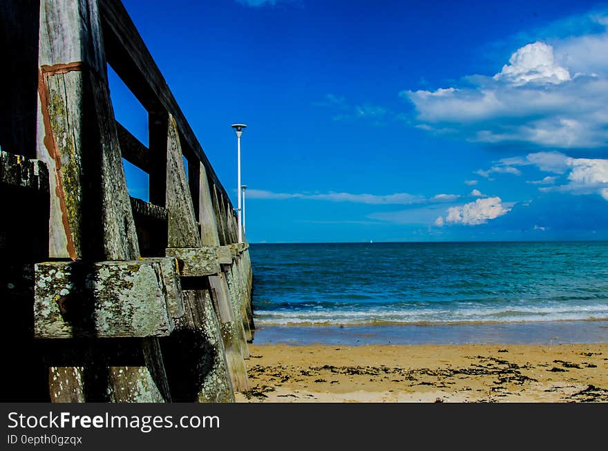 Brown Wooden Bar Near Sea Shore Under Blue Sky during Day Time