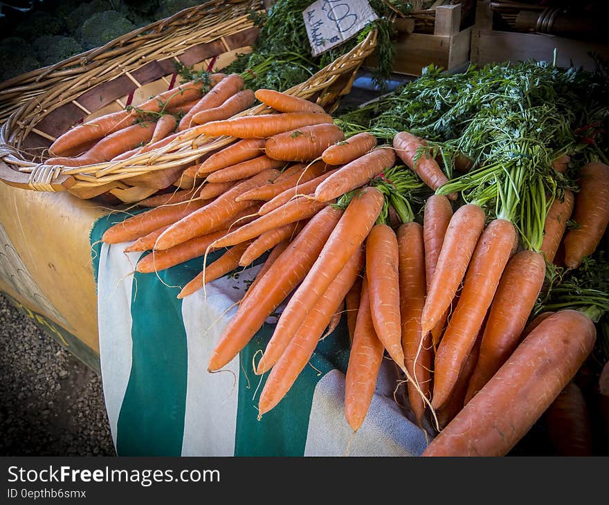 Bunches of fresh organic carrots on a market stall, some in a wicker basket. Bunches of fresh organic carrots on a market stall, some in a wicker basket.