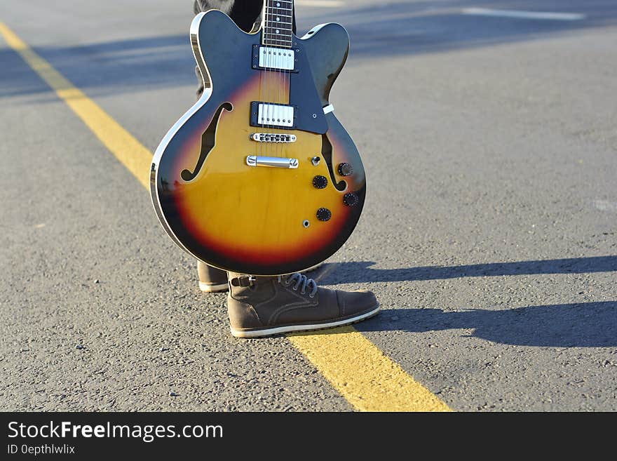 Human Holding a Brown and Black Electric Guitar during Daytime