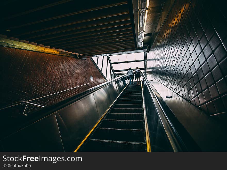 2 Person Standing on Black Escalator during Daytime