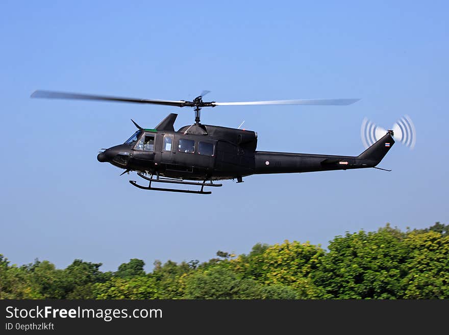 Black Helicopter Flying Above Green Trees