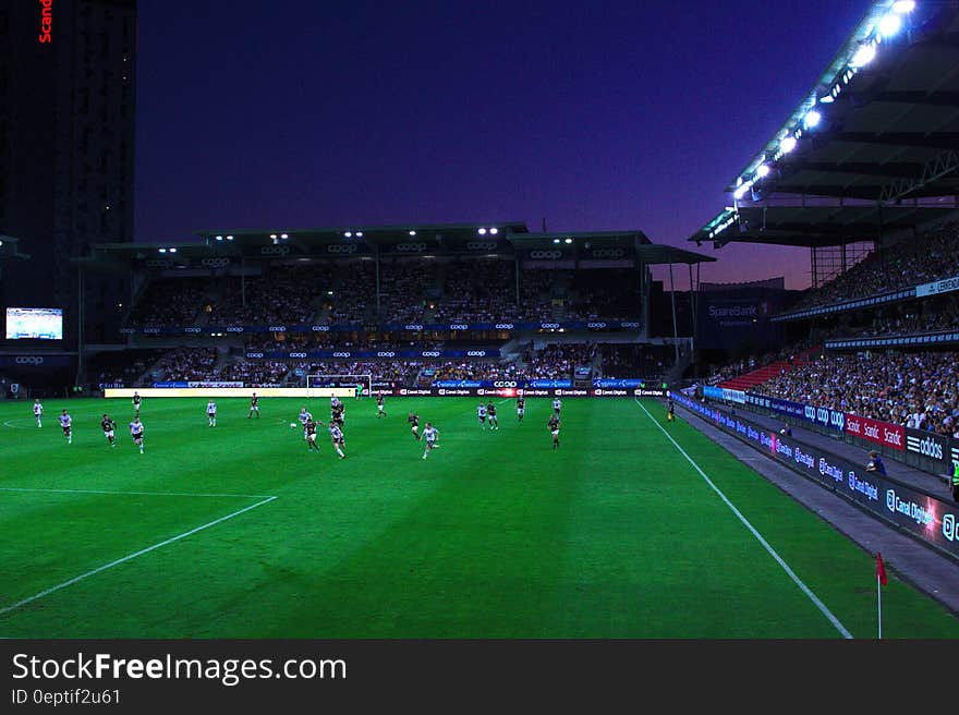 Game of football played at night in a floodlit stadium in front of a big crowd. Game of football played at night in a floodlit stadium in front of a big crowd.