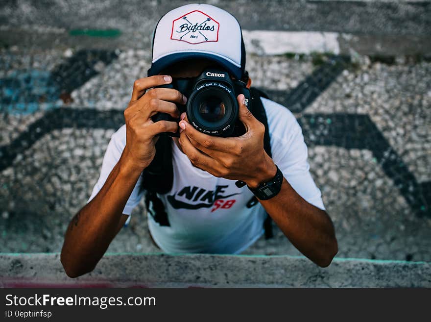 Man Wearing White Nike Sb Shirt Holding Black Dslr Camera