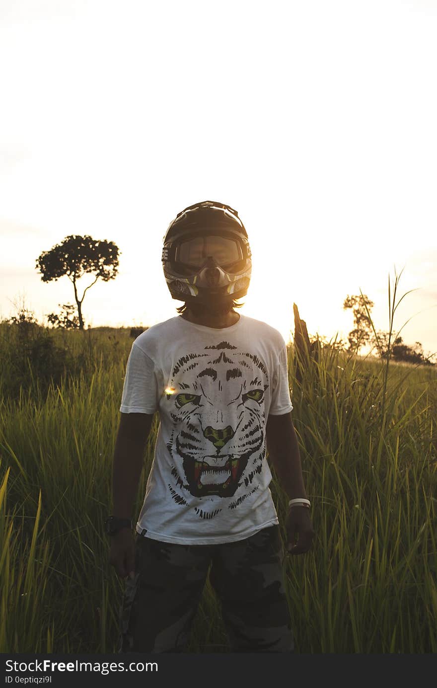 Man in Black Full Face Helmet Standing on Green Grass during Daytime