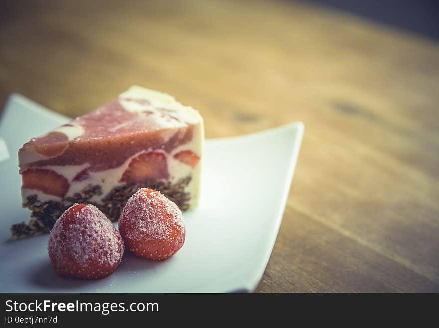 Pink and White Stawberry Cake on Top of White Ceramic Square Plate