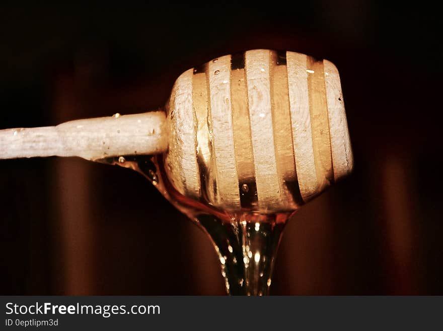 Honey flowing from a wooden honey dipper.