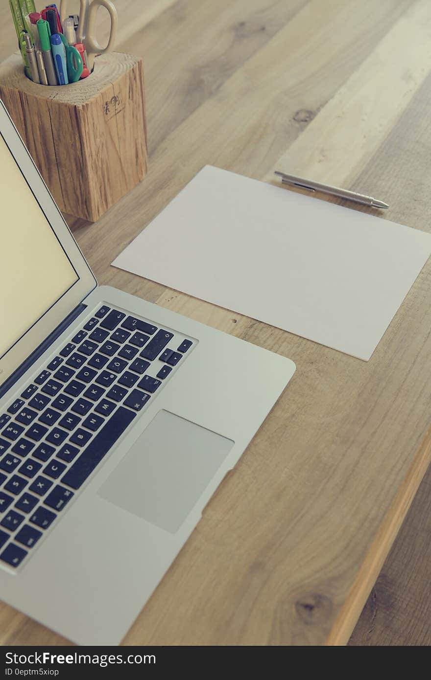 Macbook Air Beside White Paper and Click Pen on Top of Table