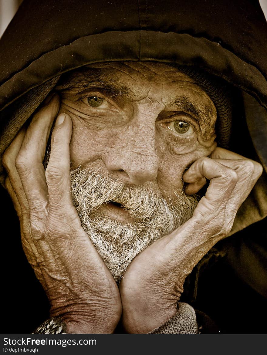 A close up portrait of an old man with a hood.