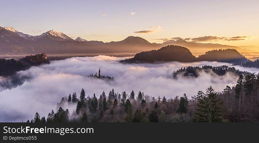 A misty morning landscape with forests and mountains.