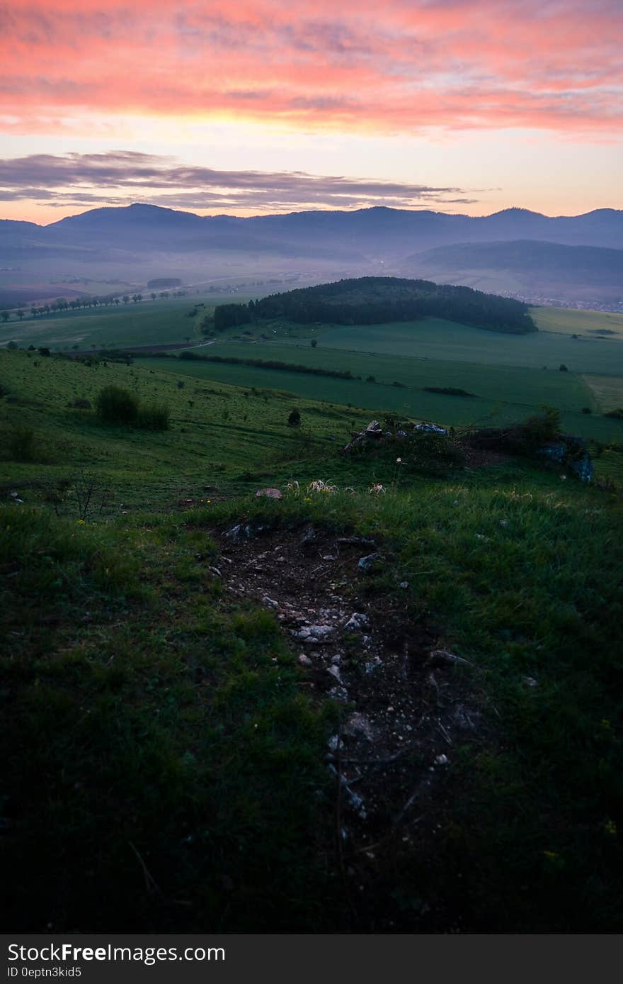 A sunset over green meadows with hills in the distance. A sunset over green meadows with hills in the distance.