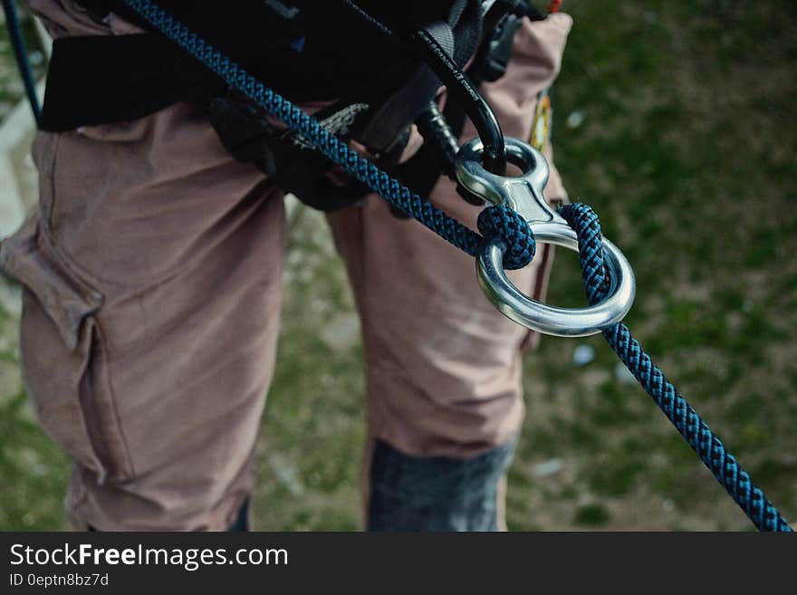 A rock climber with a rappelling rope and a ring attached to harness. A rock climber with a rappelling rope and a ring attached to harness.