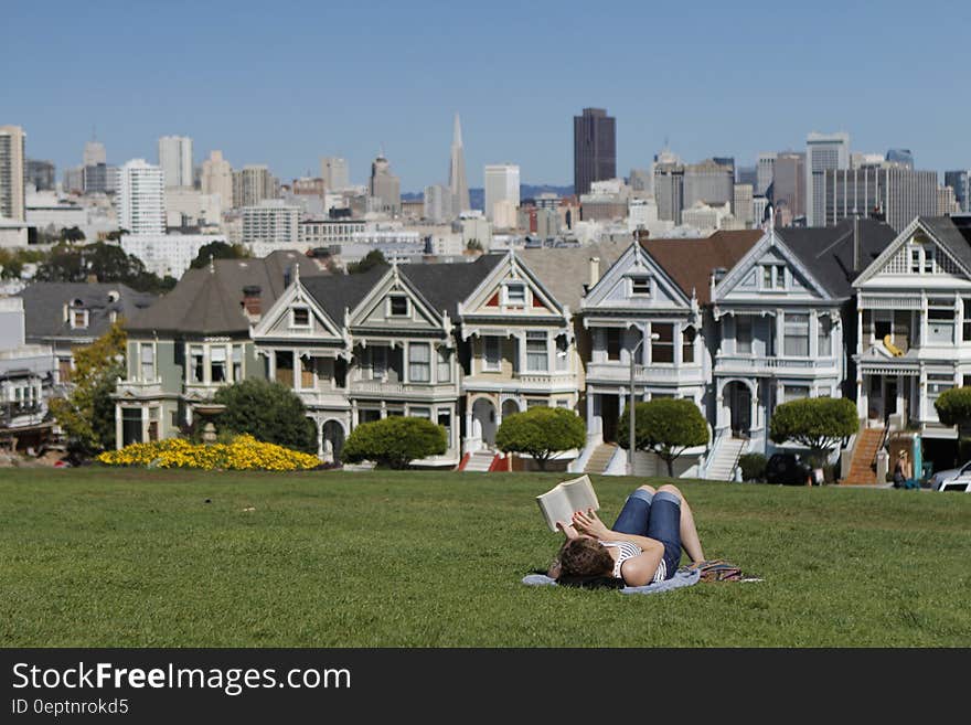 Woman Lying on White Textile in Grass Field during Daytime