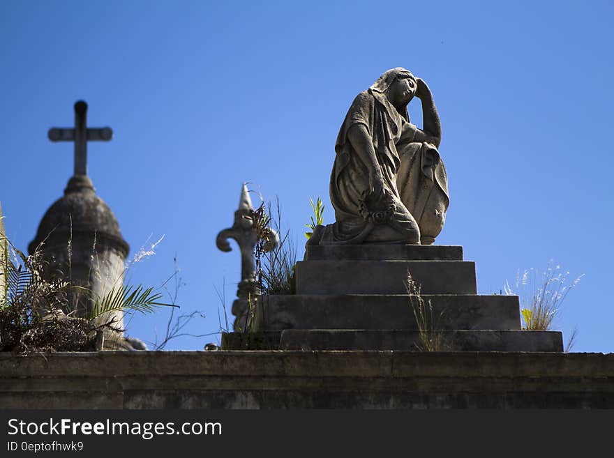 Woman Statue Near Cross during Daytime