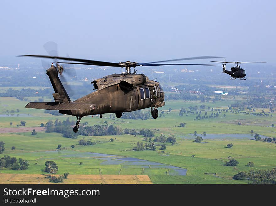 Brown Helicopter Flying Above Green Field during Daytime