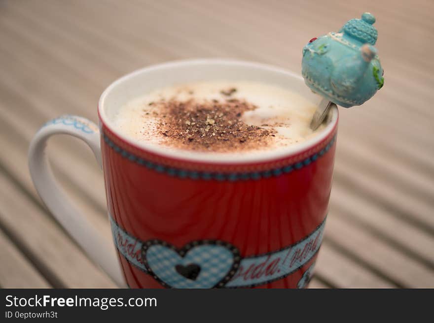 Red china coffee cup with latte and teapot decoration on spoon. Red china coffee cup with latte and teapot decoration on spoon.