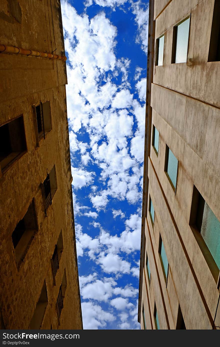 Low Angle Photography of Brown Concrete Building Under White Cloudy Blue Sky at Daytime