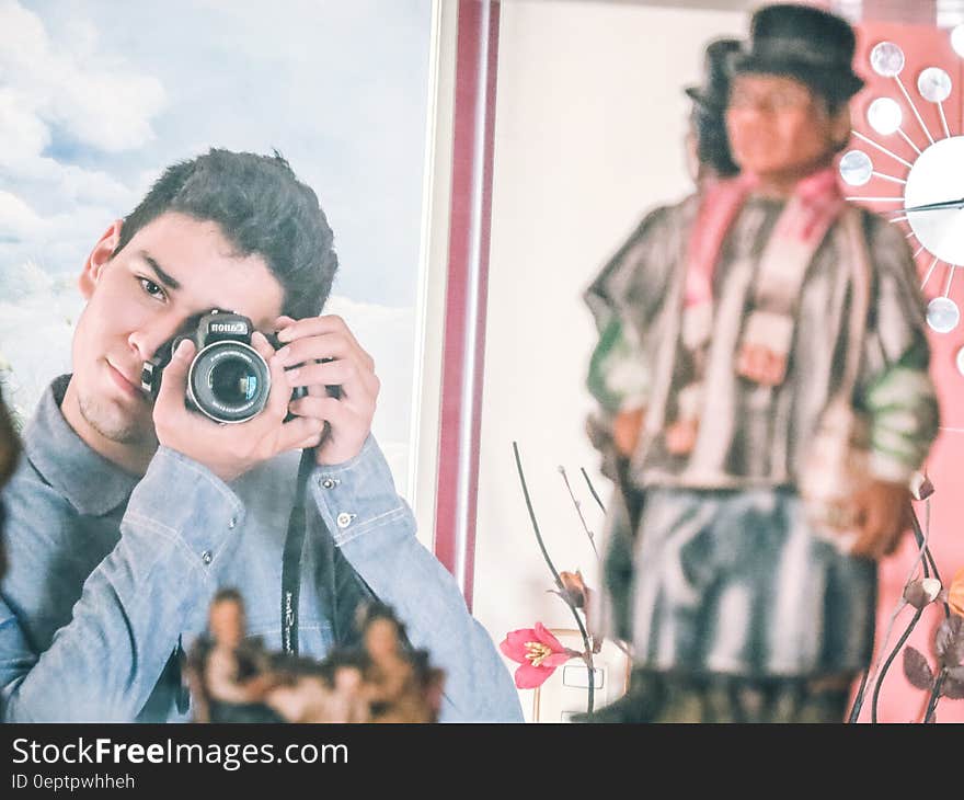 Man in Blue Denim Jacket Using Black Dslr Camera