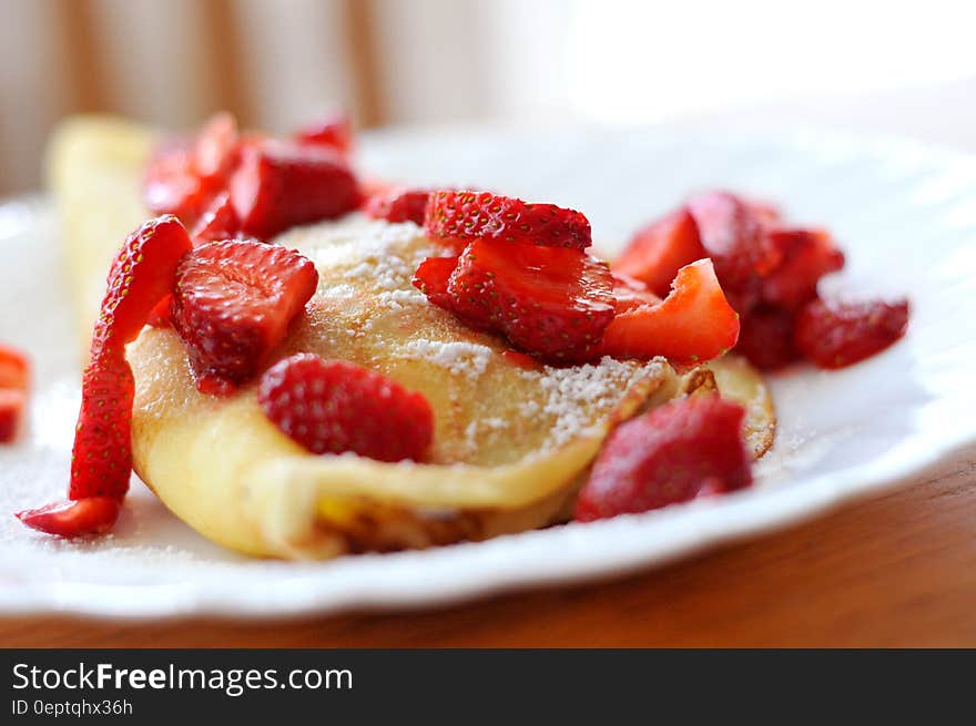 A plate of pancakes with fresh strawberries and powder sugar. A plate of pancakes with fresh strawberries and powder sugar.