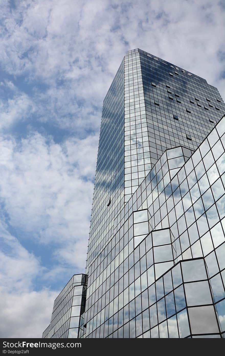 Facade of mirrored modern architecture against blue skies with white clouds. Facade of mirrored modern architecture against blue skies with white clouds.