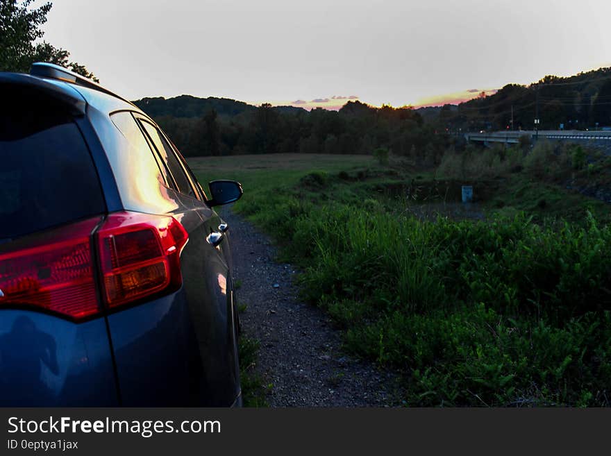 Black Suv on Rocky Road Near Green Grass