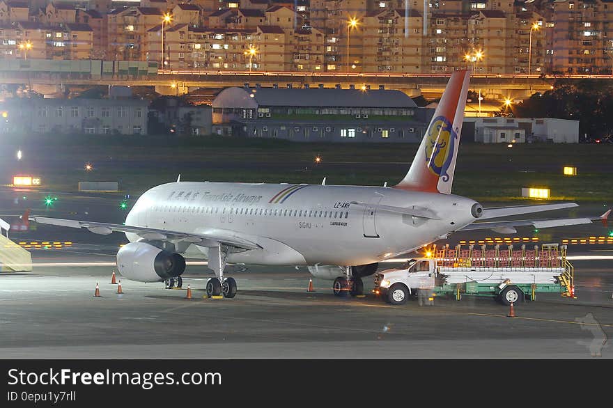 Commercial jet with fuel truck and airport workers on airport apron at night in city. Commercial jet with fuel truck and airport workers on airport apron at night in city.