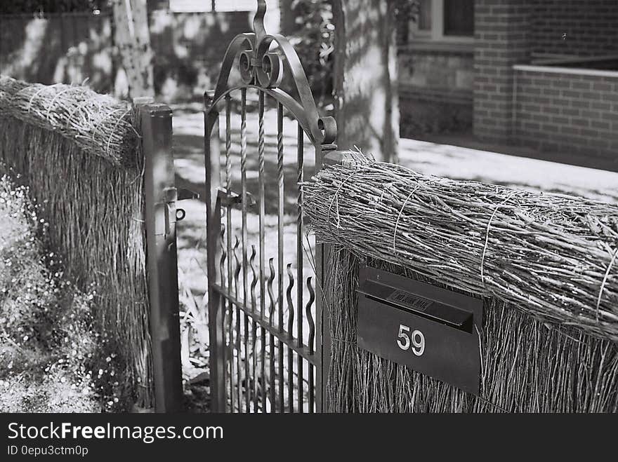 Close up of thatched fence with metal gate outside home in black and white. Close up of thatched fence with metal gate outside home in black and white.