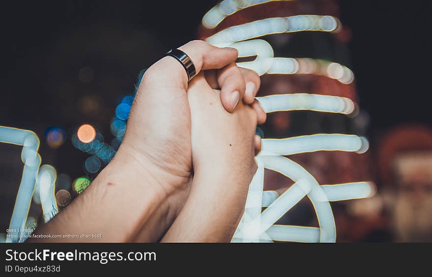 Close up of hands folded with ring on thumb outdoors at night. Close up of hands folded with ring on thumb outdoors at night.