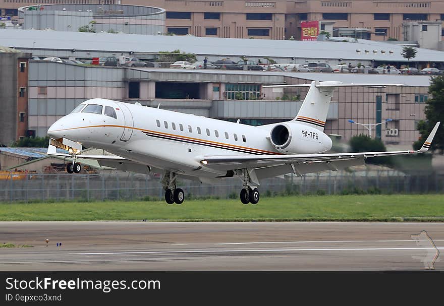 Corporate jet on take off on runway outside airport terminal on sunny day.