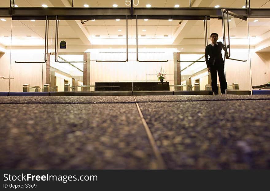 Man standing inside doorway to modern office building from low street level angle. Man standing inside doorway to modern office building from low street level angle.