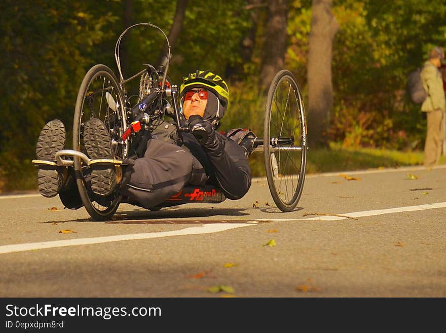 Man riding racing handcycle on roadway.