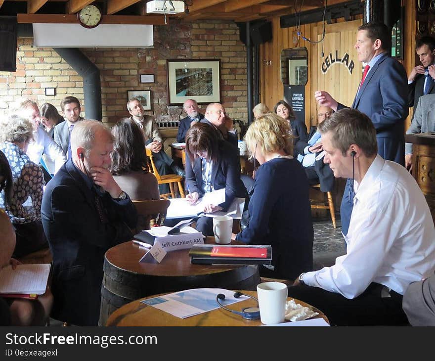 Man presenting to coworkers at business meeting held inside restaurant. Man presenting to coworkers at business meeting held inside restaurant.