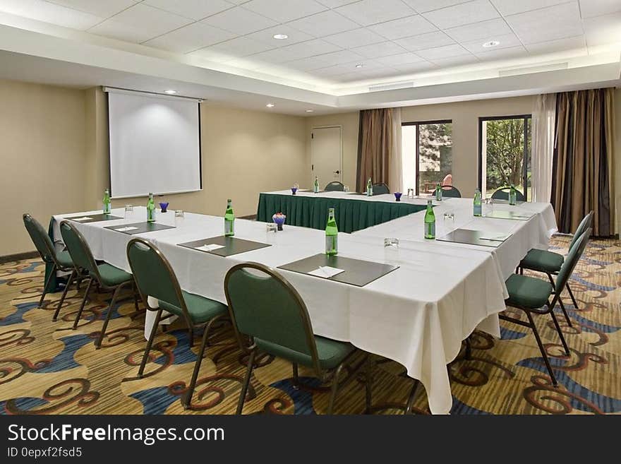 Table set in empty conference room with presentation screen. Table set in empty conference room with presentation screen.