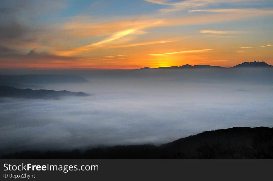 Sunset over horizon with mist covering mountain peaks. Sunset over horizon with mist covering mountain peaks.