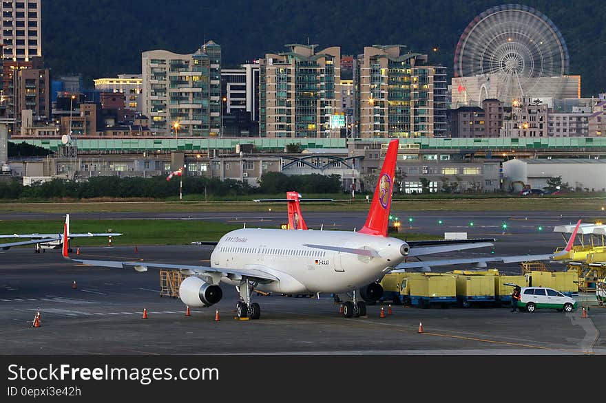 Commercial jets on runway of international airport illuminated at dusk.