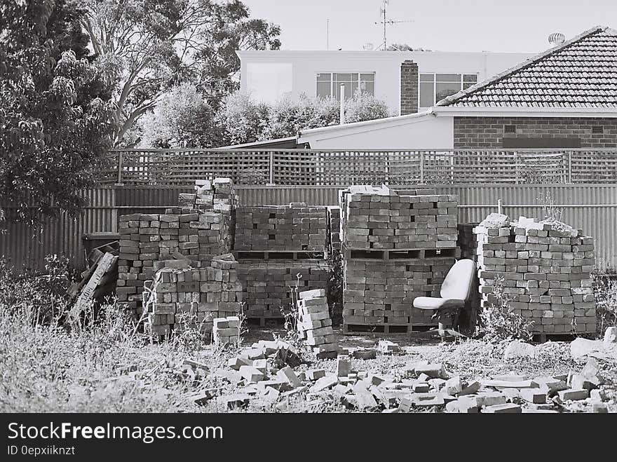 Bricks piled against fencing in backyard in black and white. Bricks piled against fencing in backyard in black and white.