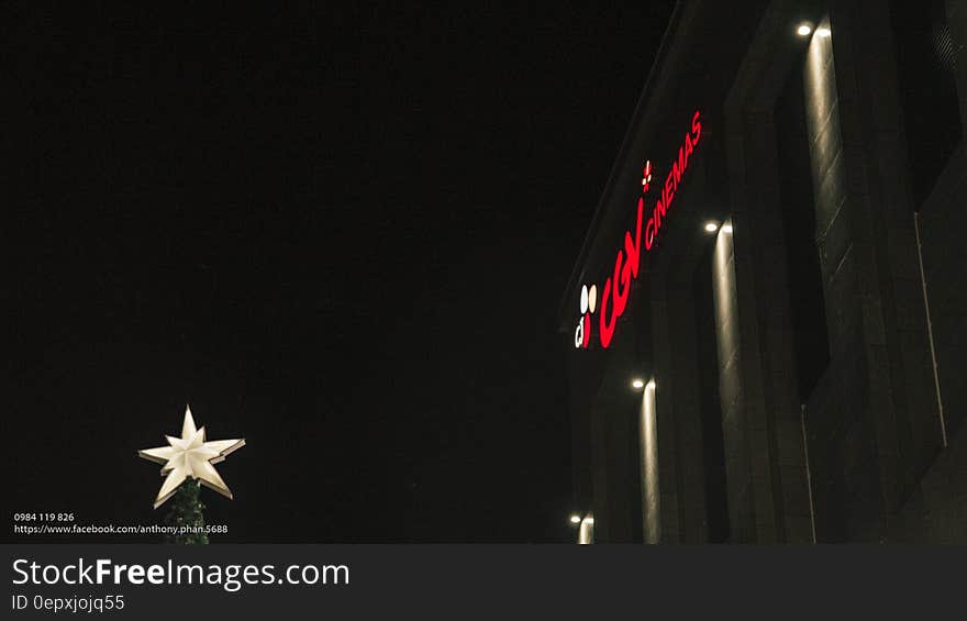 CGV in red neon lights outside building with white star at night.