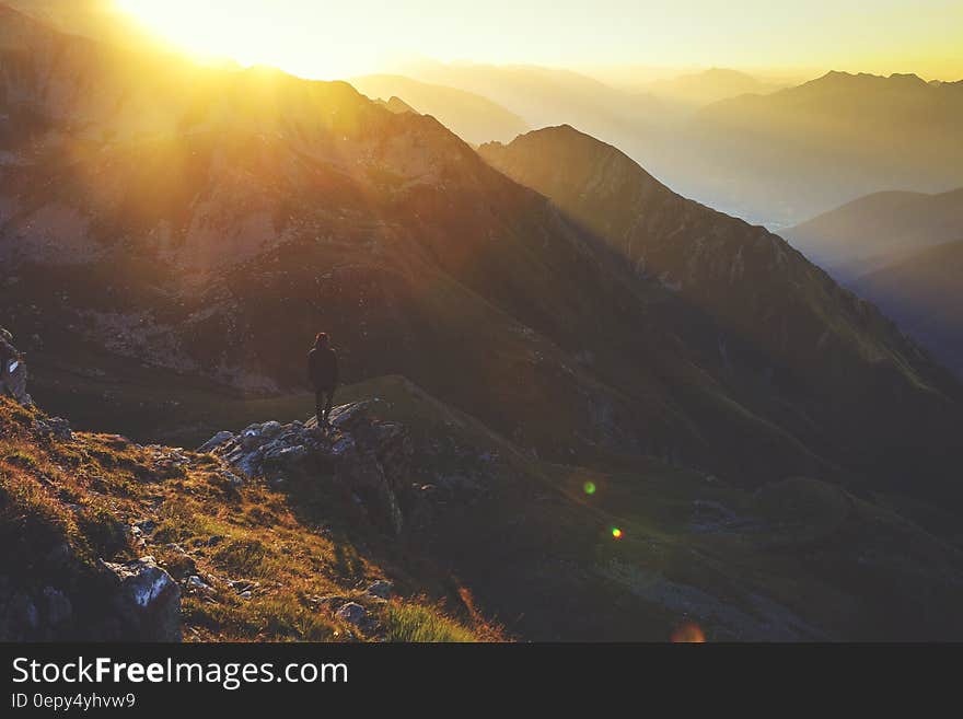 Hiker standing on rocky overlook at sunrise over mountain valley. Hiker standing on rocky overlook at sunrise over mountain valley.