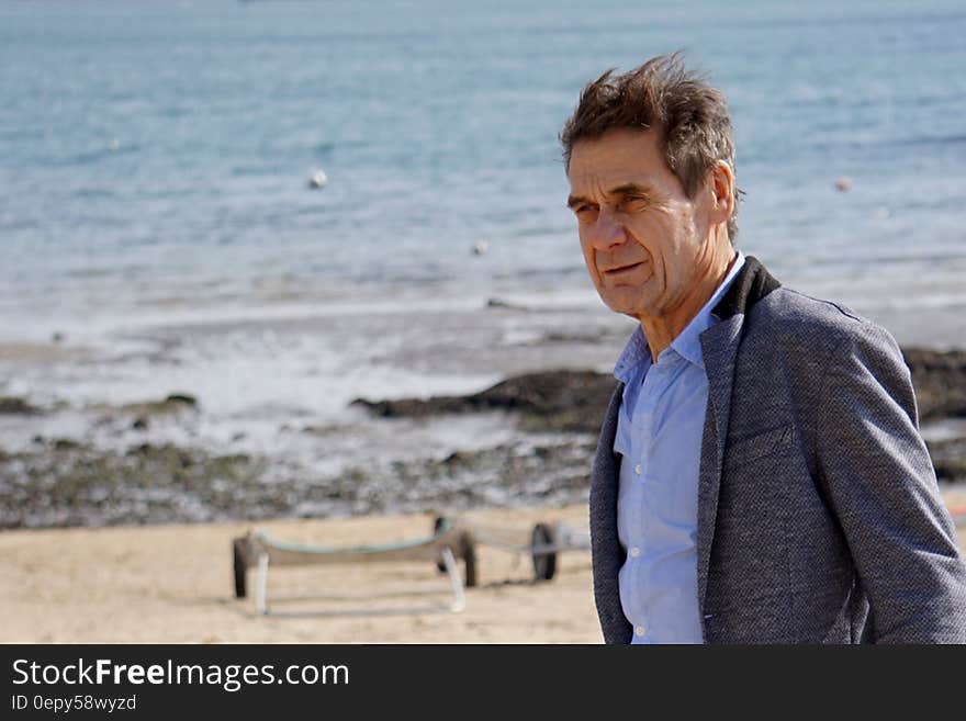 Mature man in business jacket on sandy beach. Mature man in business jacket on sandy beach.