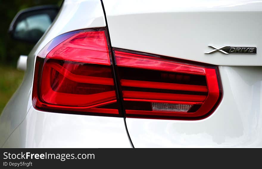 Close up of taillight, bumper, fender and trunk of white car with label X Drive. Close up of taillight, bumper, fender and trunk of white car with label X Drive.