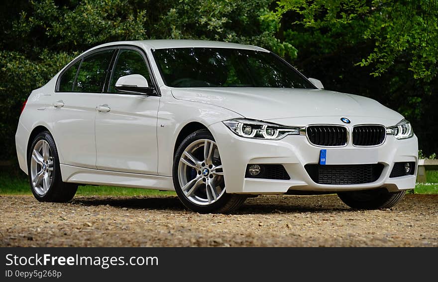 Exterior of white luxury BMW car on dirt road on sunny day. Exterior of white luxury BMW car on dirt road on sunny day.