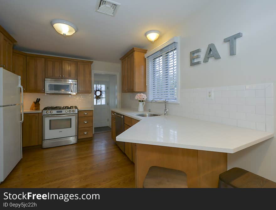 Contemporary kitchen with white appliances and wooden floors.