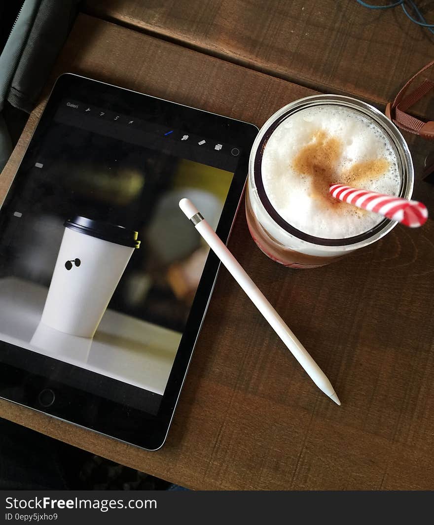 Coffee drink with straw next to tablet computer with picture of coffee drink. Coffee drink with straw next to tablet computer with picture of coffee drink.