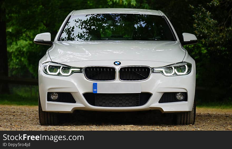 Close up of front of white luxury BMW automobile on country lane. Close up of front of white luxury BMW automobile on country lane.