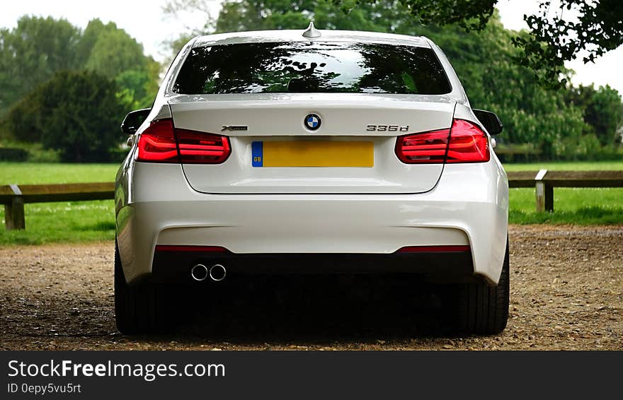 Back of luxury white BMW luxury automobile on country road. Back of luxury white BMW luxury automobile on country road.